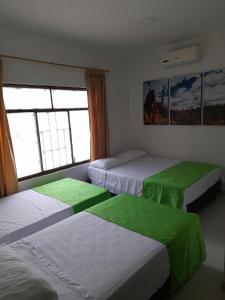 比利亚维哈Hospederia Sol del Desierto的一间卧室配有三张床,铺有绿色床单