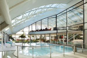 勒梅尼尔阿姆洛巴黎鲁瓦西大洋洲酒店的一座带玻璃天花板的大型游泳池