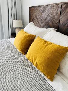 圣地亚哥Alta Vista Las Condes的一张带黄色枕头的床和木制床头板