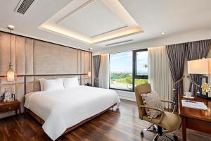 Bắc GiangRavatel Luxury Hotel Bac Giang的一间卧室配有一张床、一张桌子和一把椅子