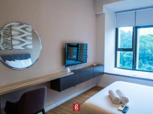 吉隆坡Ceylonz KLCC by Gsuites的一间带镜子、一张床和电视的卧室