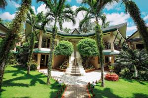 长滩岛Paradise Garden Hotel and Convention Boracay Powered by ASTON的前面有棕榈树的房子