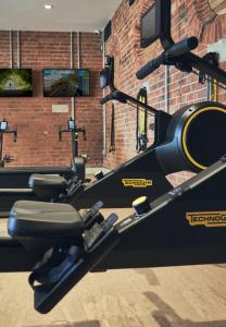 阿什伯恩Wildhive Callow Hall的一个带跑步机和砖墙的健身房