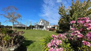 RiwakaGreen Tree Haven BnB-Riwaka Tasman Bay的院子里的白色房子,鲜花盛开