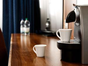 韦瑟比Jupiter Hotel Wetherby的桌子上放两个咖啡杯,配有咖啡壶