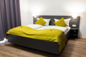 马格德堡Das ELB Boardinghouse Hotel Restaurant的卧室配有一张带黄色床单和枕头的大床。