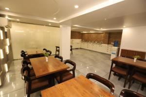 古尔冈Hotel Keshav Residency near Medanta Pure Veg的一间带木桌椅的餐厅和一间厨房
