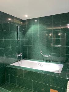 波罗维茨Villa Alexa的带浴缸的绿色瓷砖浴室