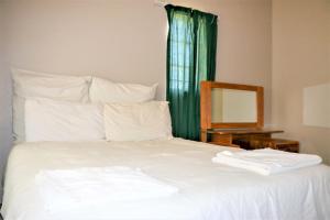 姆巴巴内Malolotja Log Cabins的一张带绿帘和镜子的白色床