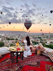 格雷梅Doors Of Cappadocia Special Cave Hotel的坐在地毯上的女人看着热气球