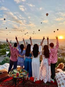 格雷梅Doors Of Cappadocia Special Cave Hotel的一群人,手臂在空中,有气球