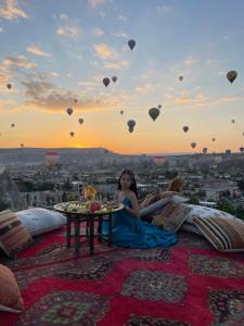 格雷梅Doors Of Cappadocia Special Cave Hotel的坐在天上带气球的地毯上的女人