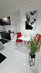 韦切什Airport Luxury Apartman 42的白色的客厅配有白色的桌子和红色的椅子