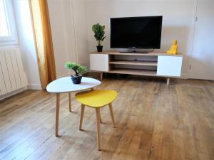 欧里亚克Appartement moderne entièrement rénové的客厅配有电视、桌子和黄色凳子