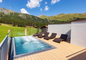 达沃斯凯斯勒库尔姆酒店的一个带椅子的甲板和一个享有山景的游泳池