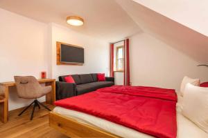 瓦尔德明兴Hotel Garni zum Schwan的一间卧室配有红色的床和一张沙发