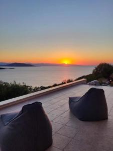 爱琴娜岛Villa Harmonia的两件东西坐在庭院里,背着日落