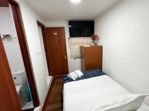 波哥大Hostal Casa del Café的小房间设有床和电视