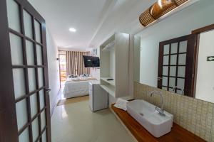 普拉亚多Praia do Forte Suites的一间带水槽的浴室和一间带床的房间