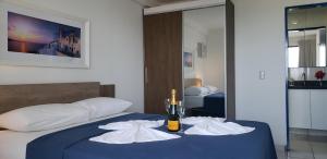 纳塔尔Natal Prime - Porto Imperial的一间卧室配有一张床、一瓶葡萄酒和毛巾