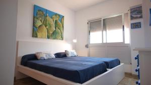 巴尔韦尔德Apartamento en La Caleta El Hierro的一间卧室配有一张带蓝色床单的床和一扇窗户。