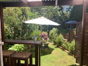 卢拉Burradoo Studio的花园里的一张带白色遮阳伞的桌子