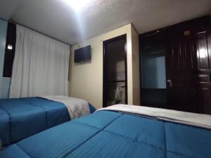 伊瓦拉Hostal Buenaventura Ibarra的酒店客房设有两张床和电视。