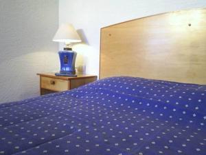 埃尔基斯科Cabañas Barrachina, Punta de Tralca的一张带蓝色被子的床和一张桌子上的台灯