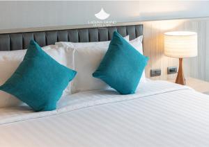 宋卡Laguna Grand Hotel & Spa Songkhla的一张带两个蓝色枕头的白色床