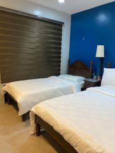 美岸Vivere Condominium的两张位于酒店客房的床,拥有蓝色的墙壁