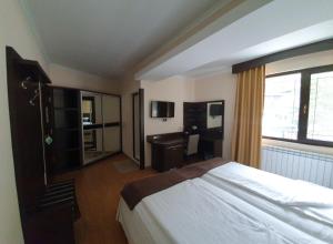 巴塔克Family Hotel Hebar的一间卧室配有一张床、一张书桌和一个窗户。