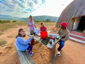 UsutuSwazi Dreams. (Nqabaneni Eco-Volunteering.)的一群人坐在小屋前的桌子上