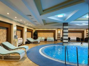阿拉木图西莫尔度假及SPA酒店的酒店大堂的游泳池,设有椅子和游泳池