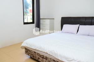 TanjungbingaSahabat Pantai Guest House Mitra RedDoorz的一间卧室配有一张白色的床和黑色床头板