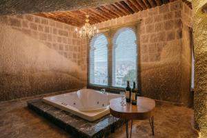 格雷梅Lunar Cappadocia Hotel的带浴缸和酒瓶桌子的浴室