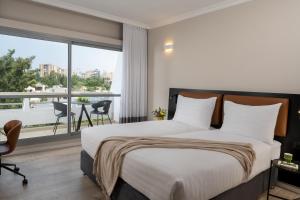 拉马特甘Kfar Maccabiah Business & Sport Hotel的一间卧室设有一张床和一个大窗户
