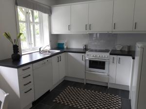 莫斯Huset i skogen的厨房配有白色橱柜、水槽和炉灶。
