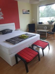 不莱梅Zentrales Apartement Bremen的一间卧室配有白色的床和两张红色椅子