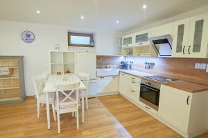 耶塞尼克Apartmán Casia的厨房配有白色橱柜和桌椅