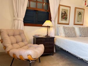 布希奥斯Pousada Blanca Mar的一间卧室配有一张床、一把椅子和一盏灯