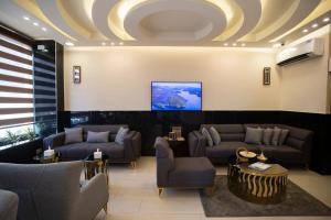 亚喀巴TAJ Hotel的大堂配有沙发和天花板上的电视