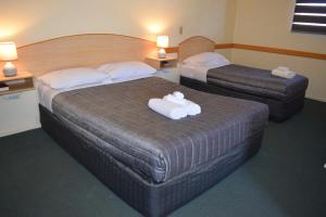 华威沃维克瓦因斯汽车旅馆的两张位于酒店客房的床,配有毛巾