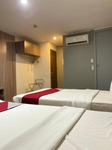 马尼拉Anex Hotel near US Embassy的酒店客房设有两张床和一个衣柜。