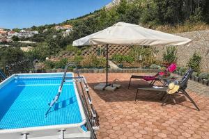 斯坦尼奇Family friendly apartments with a swimming pool Stanici, Omis - 18676的一个带遮阳伞、桌子和椅子的游泳池