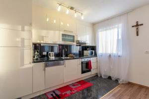 斯坦尼奇Family friendly apartments with a swimming pool Stanici, Omis - 18676的厨房配有白色橱柜,墙上有十字架