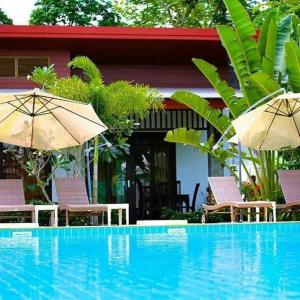 高兰Arthaya Villas - SHA Extra Plus的房屋旁的游泳池配有椅子和遮阳伞