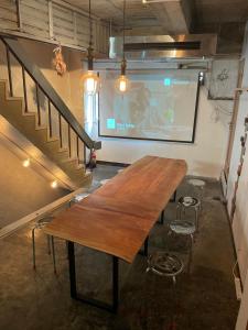别府Beppu hostel&cafe ourschestra的放映屏幕的木桌