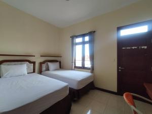 登巴萨Adi Pelita Sari Bali的酒店客房设有两张床和窗户。