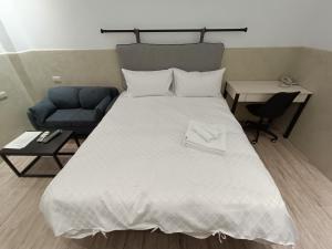 台南No 9 Hotel-九號文旅的卧室配有一张白色大床和一张蓝色沙发。