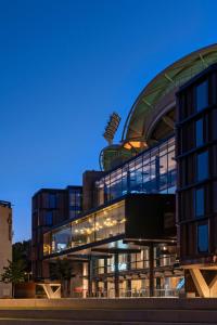 阿德莱德Oval Hotel at Adelaide Oval的黄昏时有弧形屋顶的大型玻璃建筑